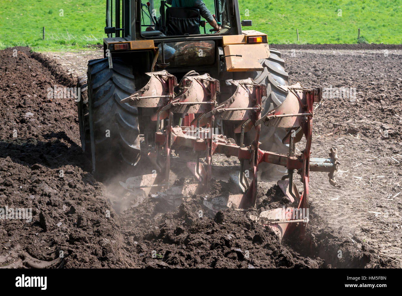 Close up del trattore arare un campo nel Cheshire su un soleggiato inizio giornata d'estate. Foto Stock