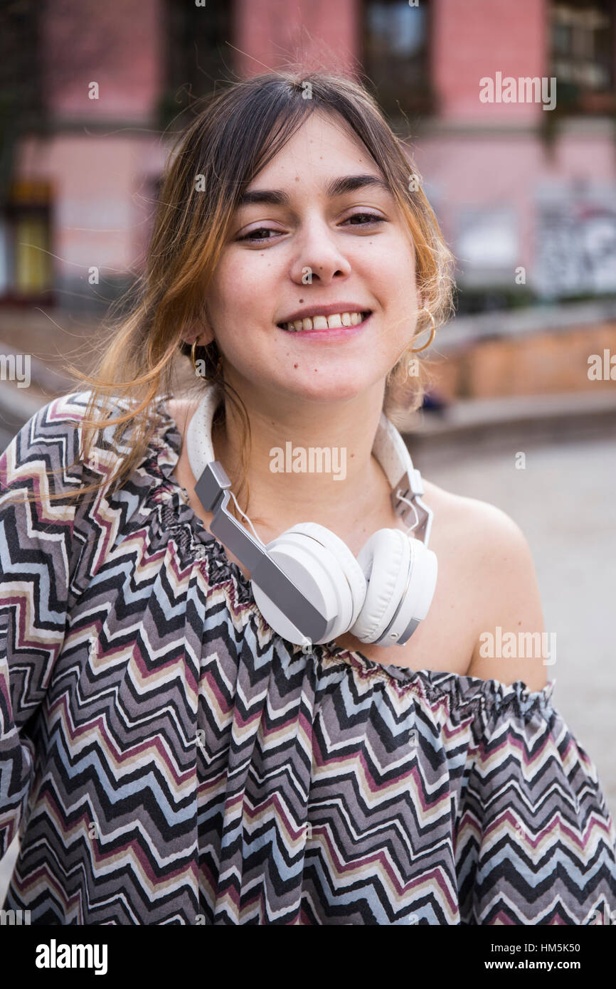 Ritratto di donna sorridente indossando le cuffie mentre in piedi in città Foto Stock