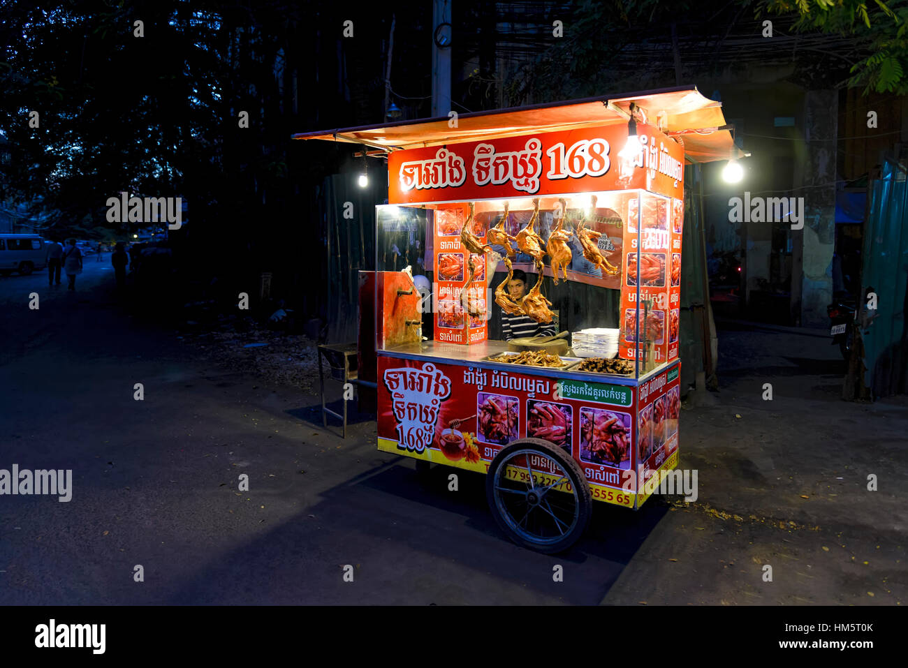 Phnom Penh Cambogia - 30 dicembre 2016: vista di un venditore ambulante di anatra arrosto all'interno il suo carrello, in attesa per i clienti lungo una strada Foto Stock