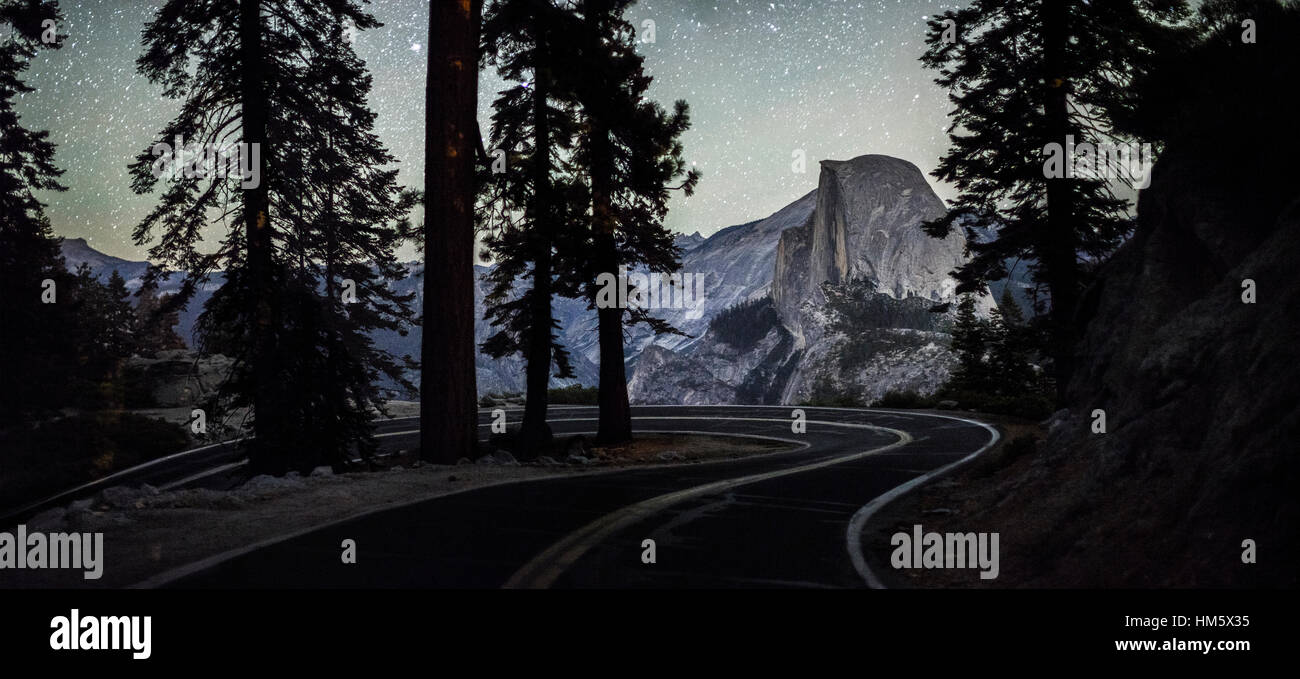 Road passando da silhouette di alberi nel Parco Nazionale di Yosemite di notte Foto Stock