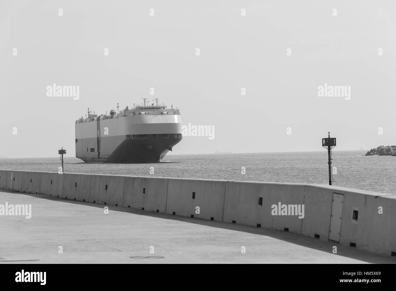 Nave oceano porto entrata attraverso il porto di pontili e segnalatori luminosi in bianco e nero. Foto Stock