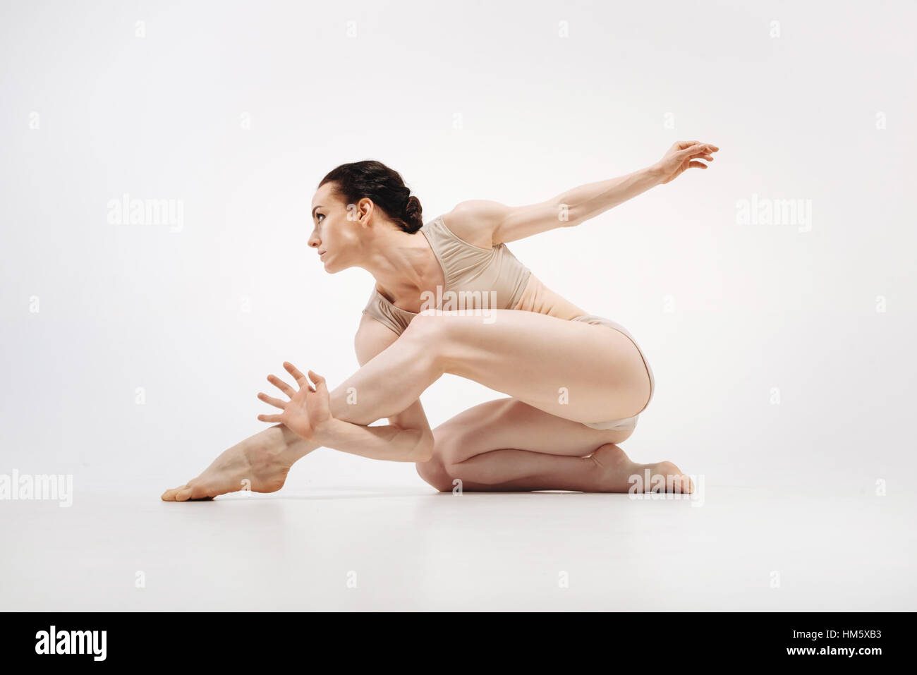 Muscoloso giovane atleta stretching in colore bianco studio Foto Stock