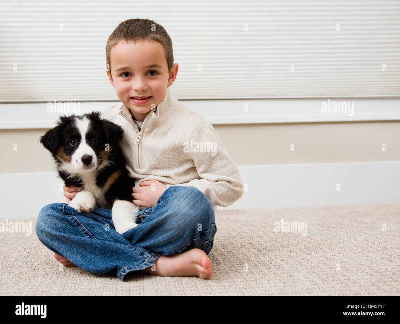 Ragazzo seduto con cucciolo su un tappeto Foto Stock