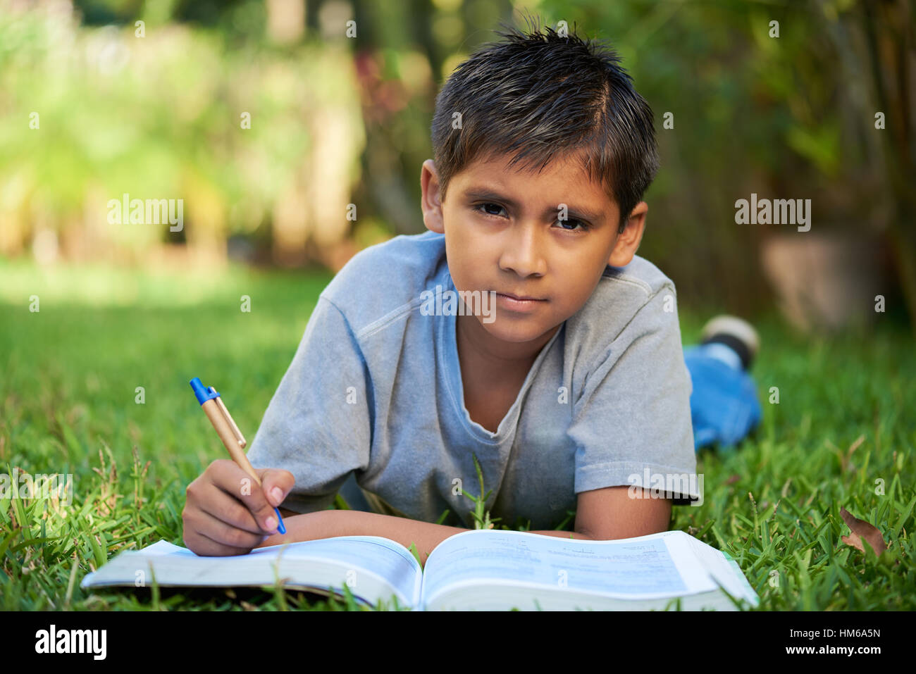 Kid posa sul prato con un libro aperto presso il parco Foto Stock