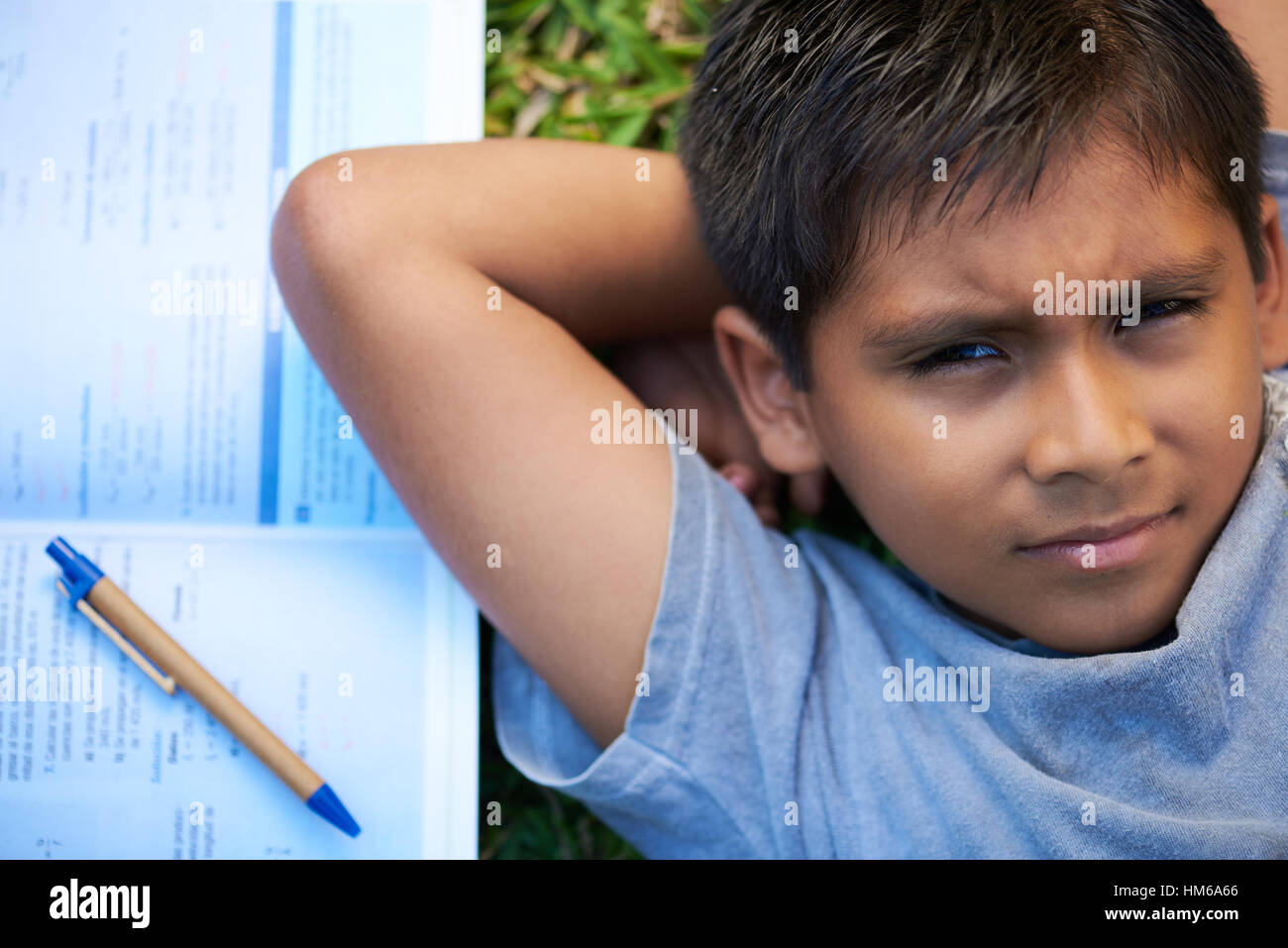 Kid recante sulla sua schiena sul prato con un libro accanto a lui Foto Stock