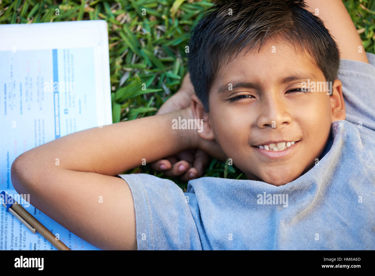 Piccolo ragazzo impara a erba con libro e penna Foto Stock
