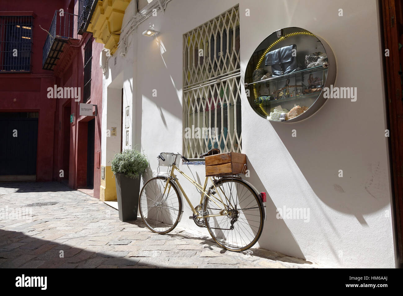 Una bicicletta si appoggia contro una parete shop a Siviglia, Spagna Foto Stock