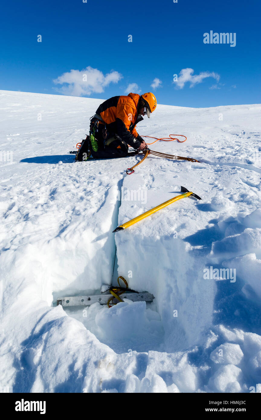 Guide di ghiaccio di scavo ancore di neve per tenere le funi per entrare in un crepaccio sulle pendici del monte Erebus in Antartide. Foto Stock