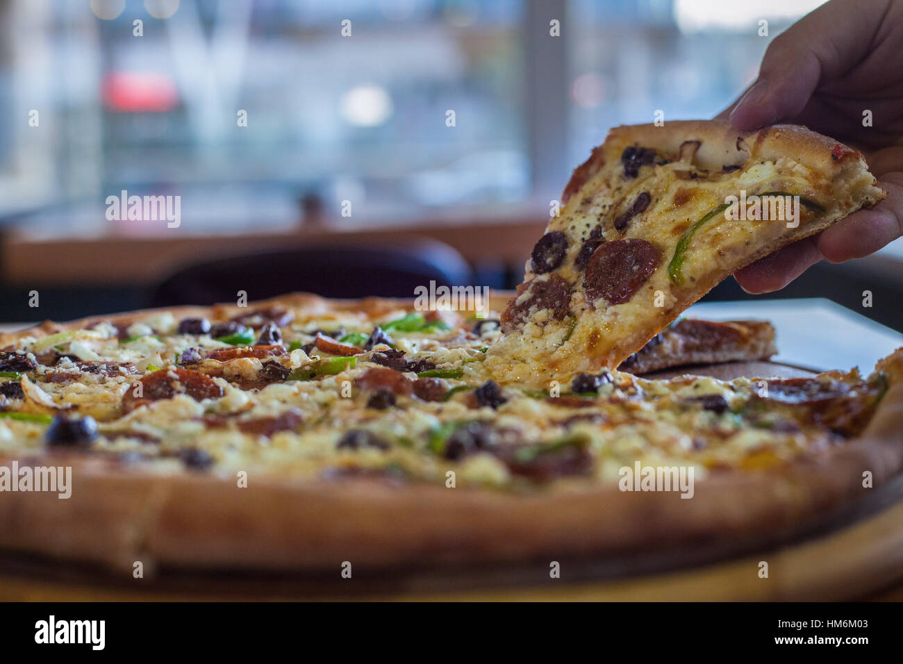 La mano afferra un trancio di pizza Foto Stock