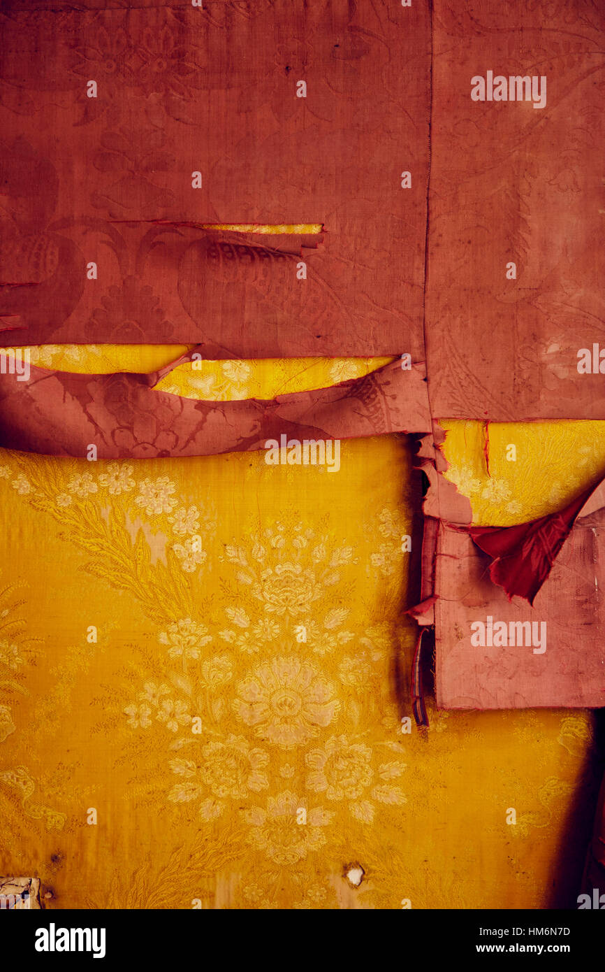 Panno vecchio di velluto nei colori giallo rosso e il pattern con fiori rotto e usurato Foto Stock