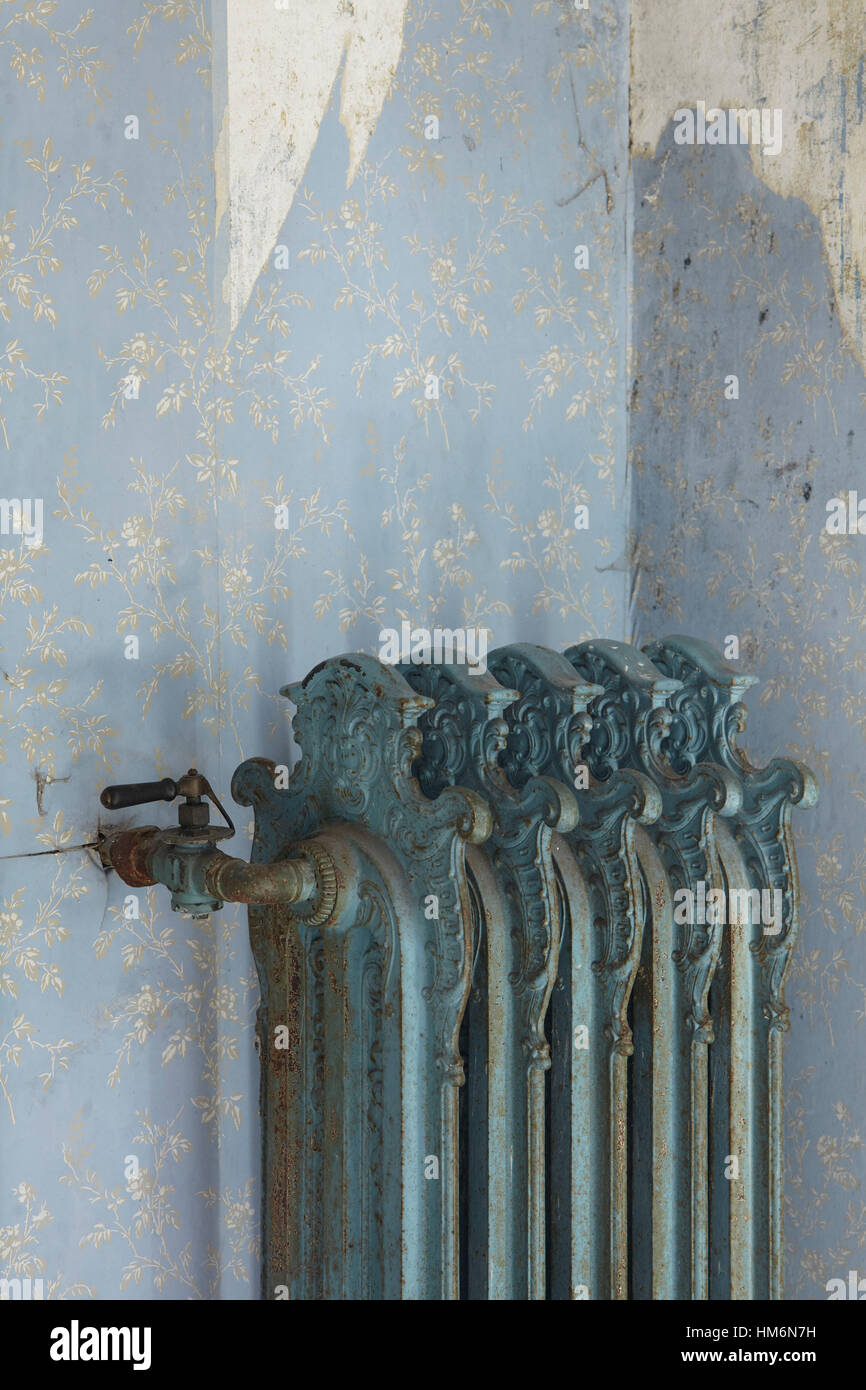 Antique vecchio radiatore di fronte ad una parete in una camera con pelato di sfondo blu Foto Stock