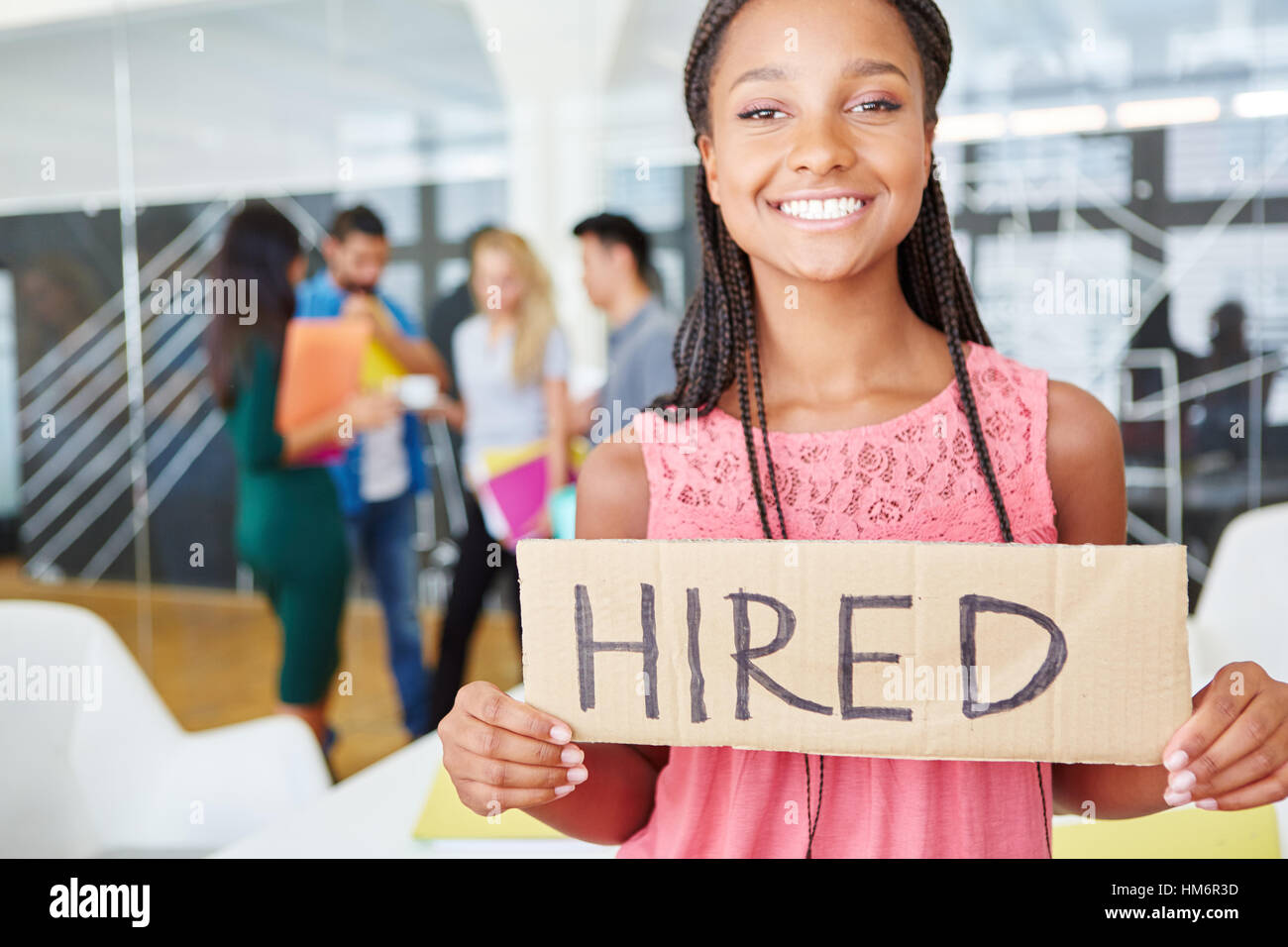 Donna che mantiene segno vuoto con la parola 'ingaggiato' permanente al start-up office Foto Stock