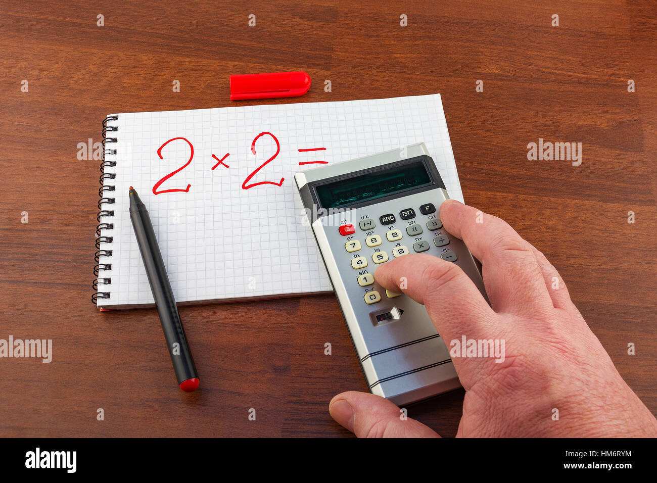 Mano d'uomo spinge il pulsante della calcolatrice risolvendo la seguente equazione Foto Stock