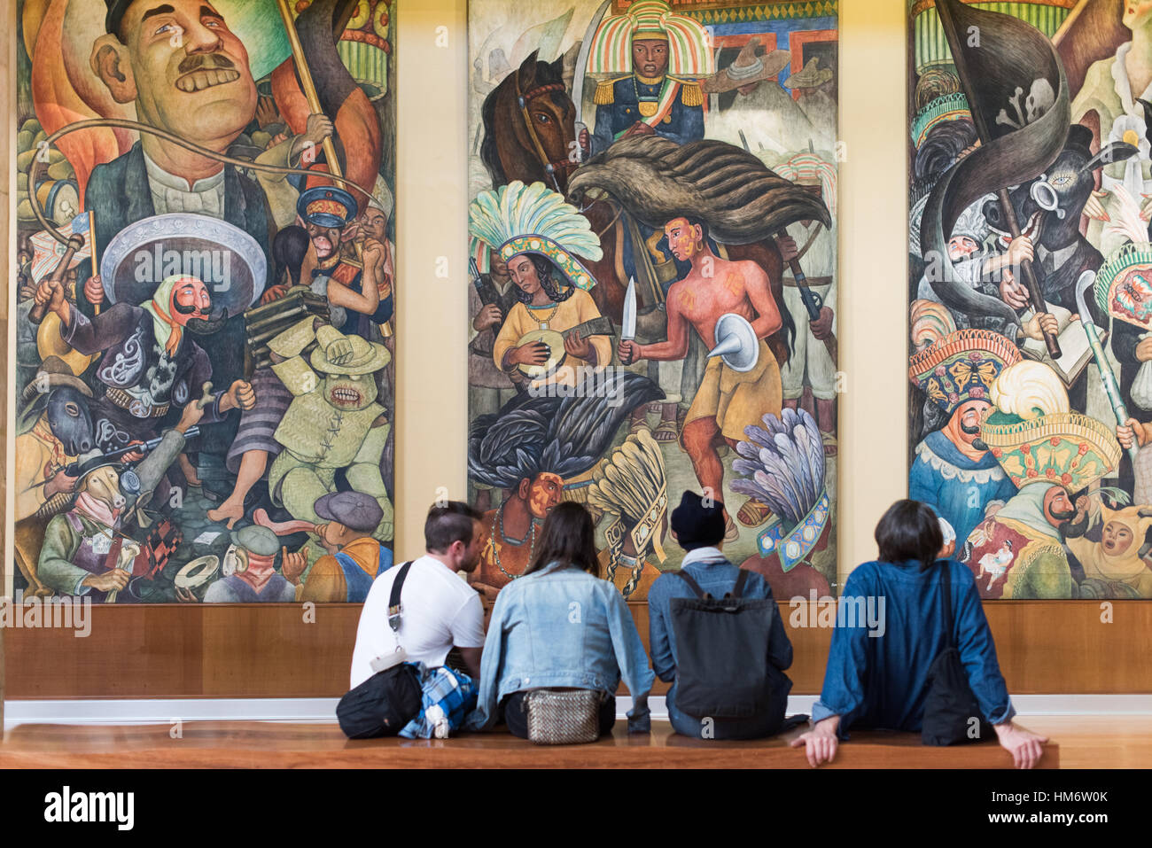 Diego Rivera Mural Palacio De Bellas Artes città del Messico // CITTÀ DEL MESSICO, Messico - i visitatori siedono di fronte a un murale del 1936 di Diego Rivera intitolato Carnevale della vita messicana (Carnaval de la vida mexicana) nel Palacio de Bellas Artes. Il murale è una delle numerose opere principali di Rivera ospitate all'interno del palazzo, che funge da principale luogo culturale e Teatro Nazionale del Messico. Il Palacio de Bellas Artes presenta un distintivo mix architettonico, con un esterno neoclassico e Art Nouveau e un interno Art Deco. Completato nel 1934 dopo quasi tre decenni di costruzione, l'edificio Foto Stock