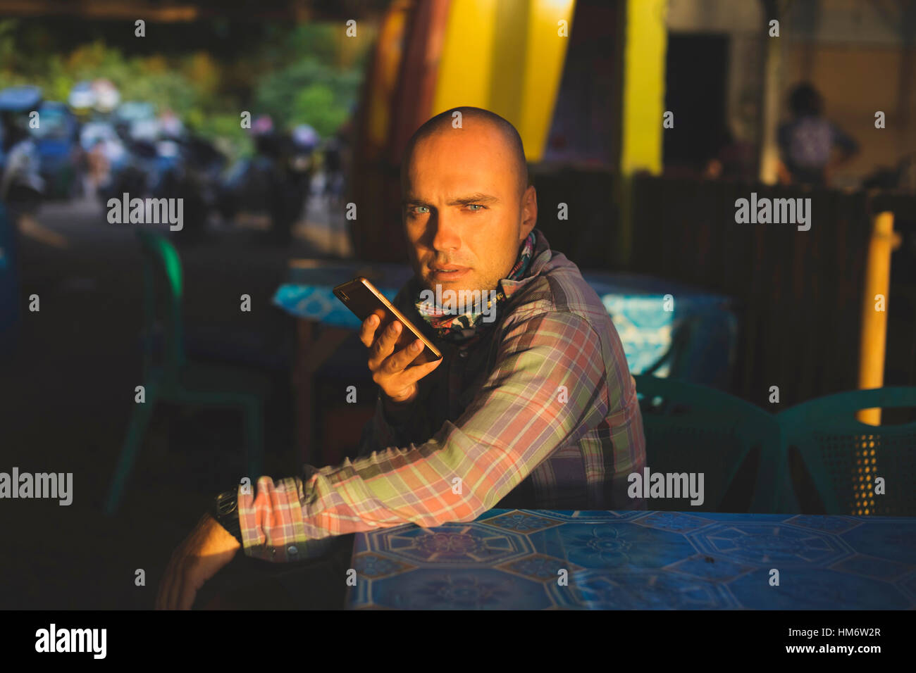 Ritratto di uomo con smart phone seduta a tavola Foto Stock