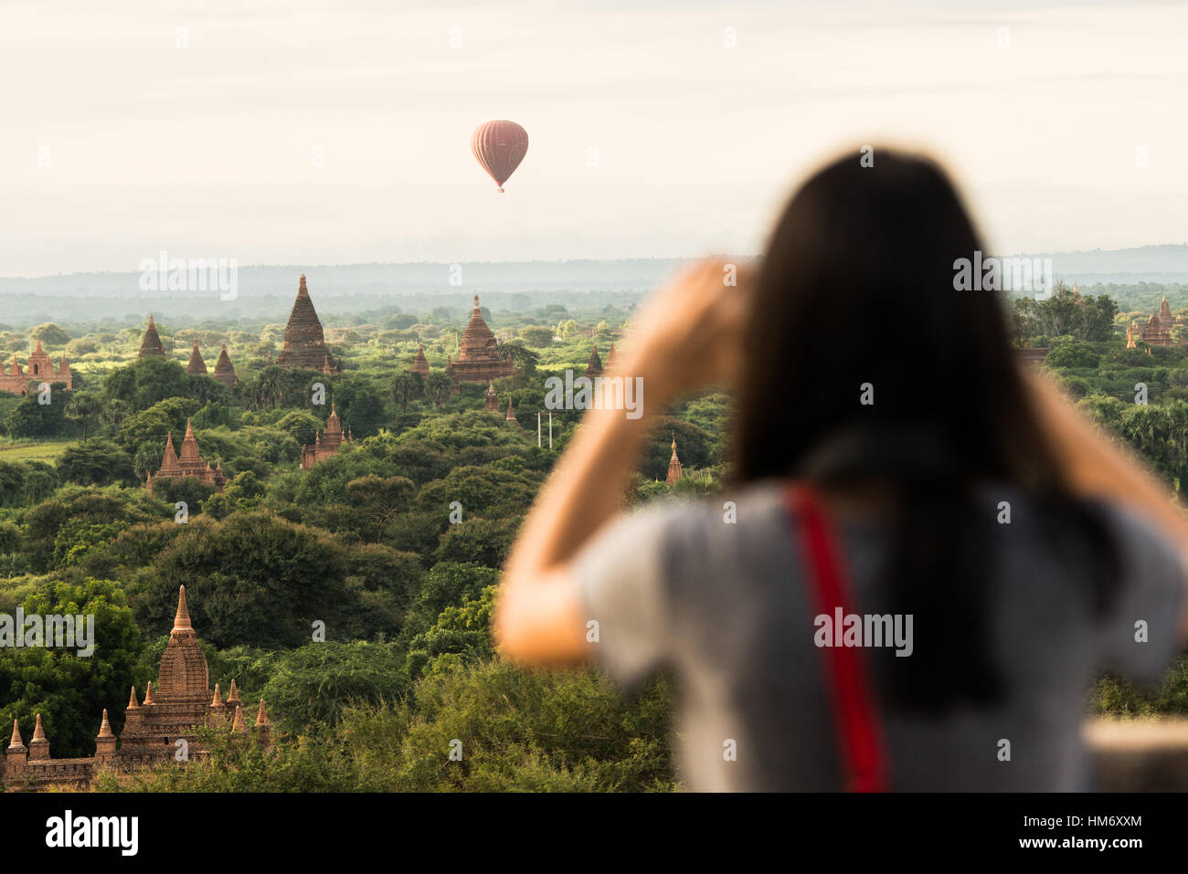 BAGAN, Myanmar - le mongolfiere volano sopra la nebbiosa pianura di Bagan all'alba. Le sagome di antichi templi e pagode si estendono attraverso il paesaggio sottostante. La luce dorata e soffusa illumina la scena, creando un'atmosfera eterea su questo sito patrimonio dell'umanità dell'UNESCO. Foto Stock