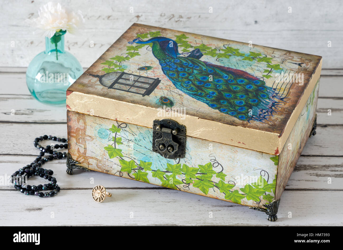 Una scatola di gioielli decoupaged con un pavone e dorata con foglia oro Foto Stock