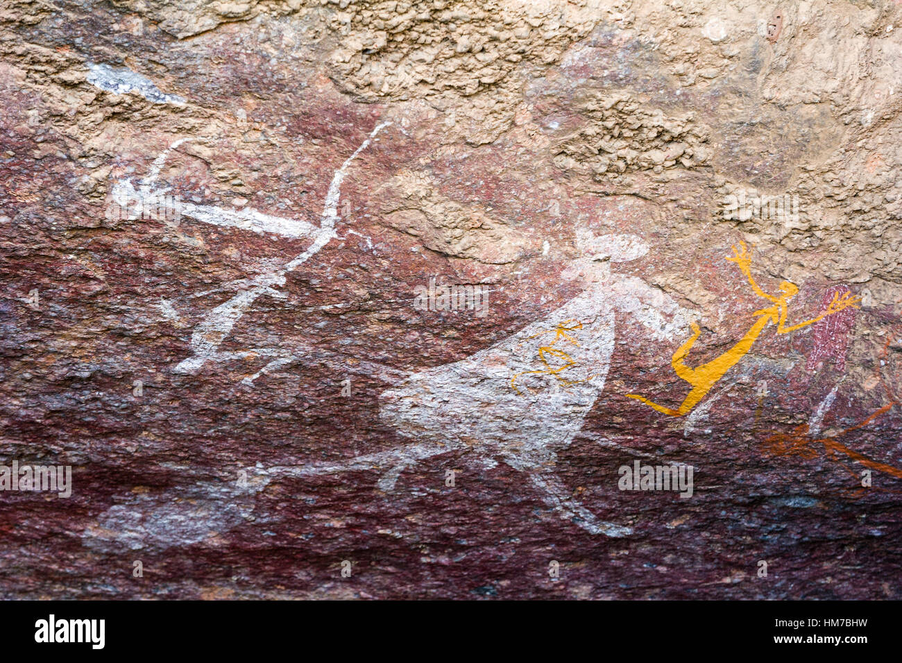 Un antica immagine di un canguro e figure umane dipinte in un aborigeno rock pittura galleria d'arte. Foto Stock