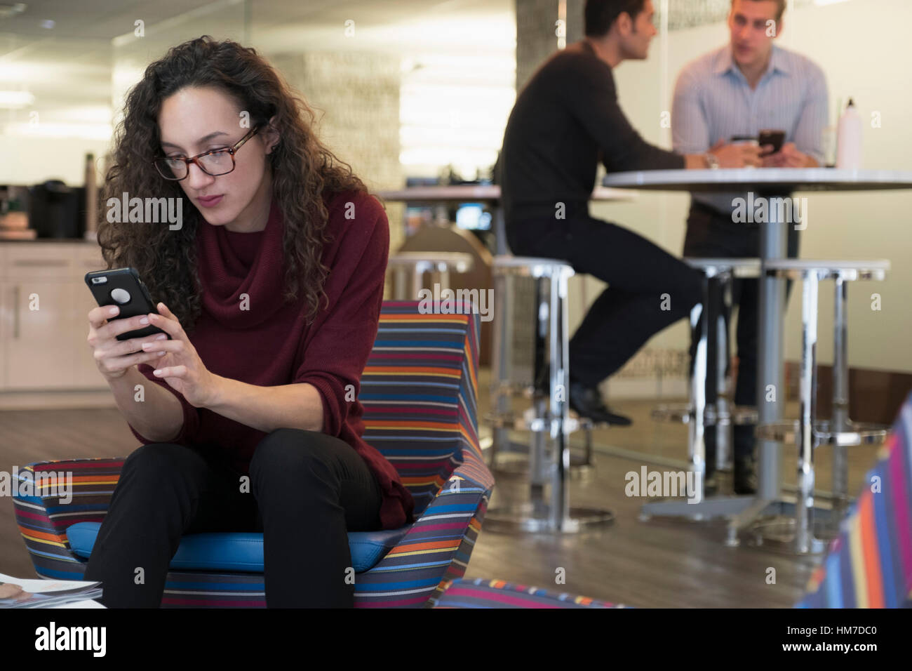 Giovane donna utilizzando il telefono cellulare in area comune Foto Stock
