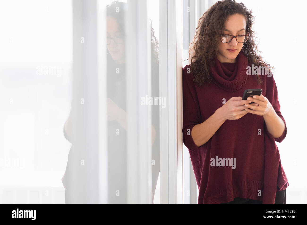 Giovane donna appoggiata sulla parete di vetro e messaggistica di testo Foto Stock