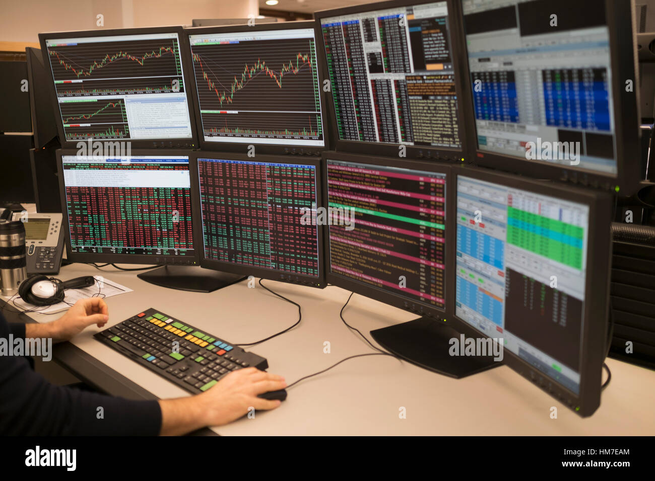 Giovane uomo che lavora sul gruppo di monitor per computer Foto Stock