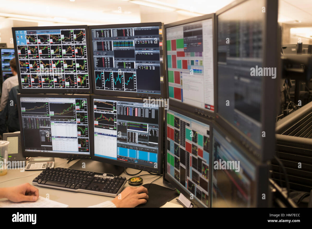 Giovane uomo che lavora sul gruppo di monitor per computer Foto Stock