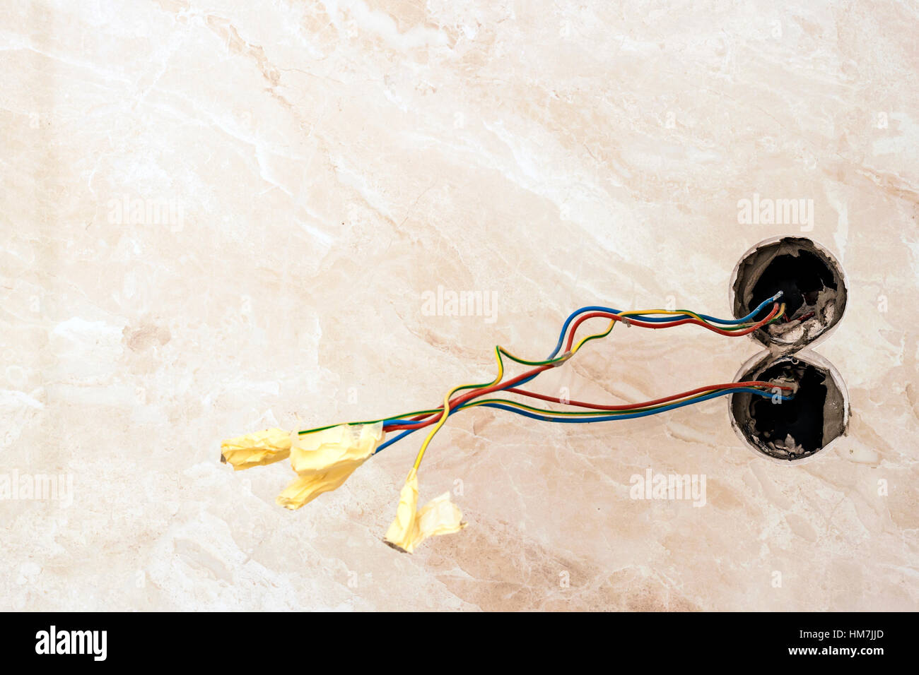 Opere di finitura a appartamento ristrutturato. Cablaggio elettrico dell'installazione. Apparecchiature elettriche i fili esposti sporgente dalla presa sulla nuova piastrelle parete coperta Foto Stock