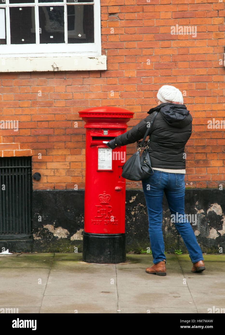 Donna inviare una lettera in un rosso rotondo post box Foto Stock