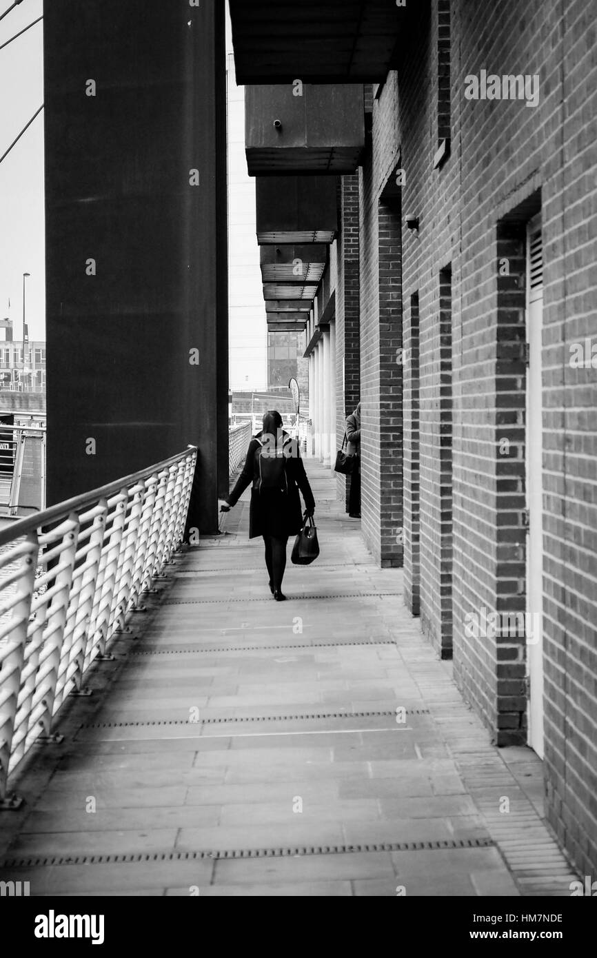 A piedi femmina per lavorare in The Granary Wharf area di Leeds, West Yorkshire. Foto Stock
