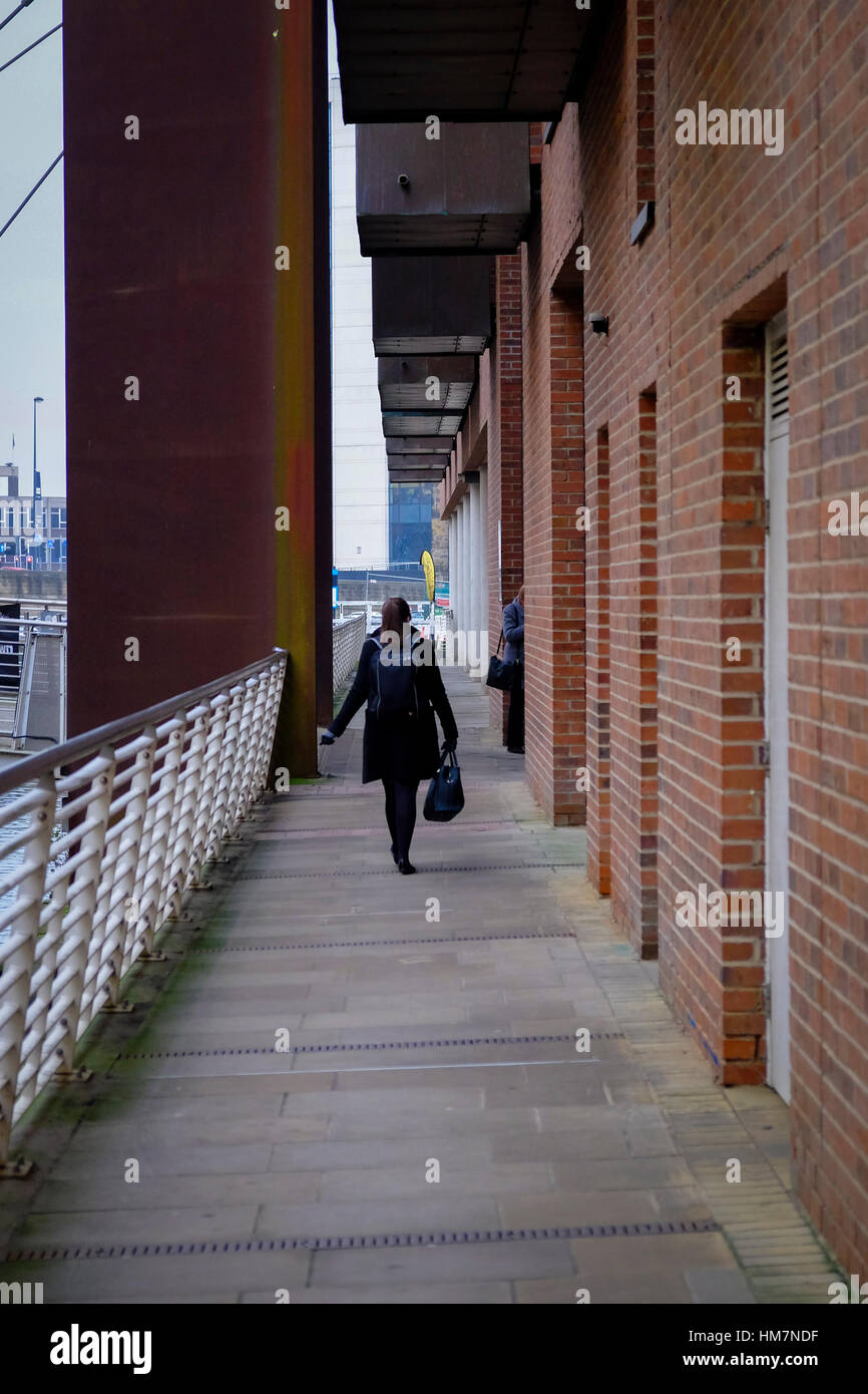 A piedi femmina per lavorare in The Granary Wharf area di Leeds, West Yorkshire. Foto Stock