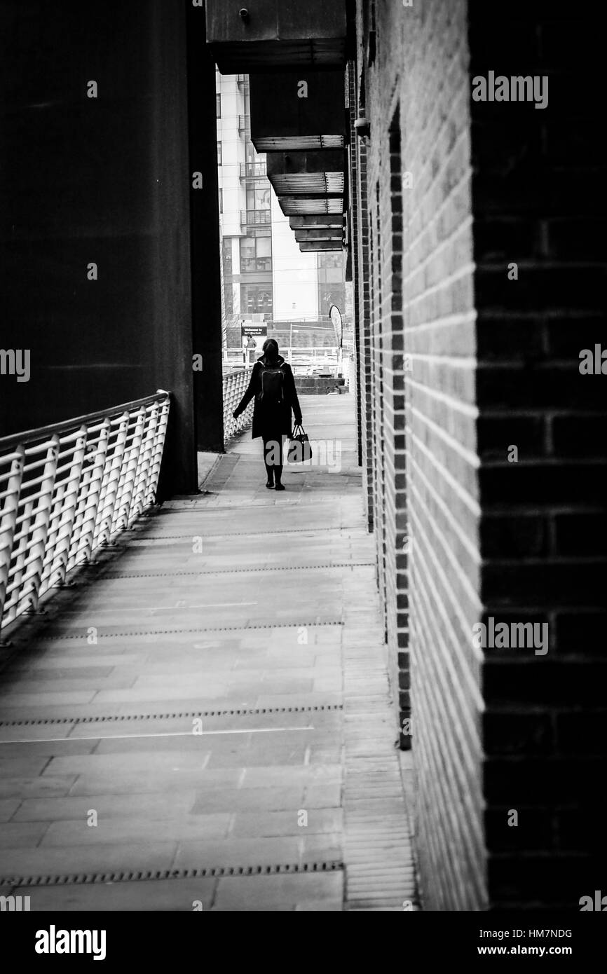 A piedi femmina per lavorare in The Granary Wharf area di Leeds, West Yorkshire. Foto Stock