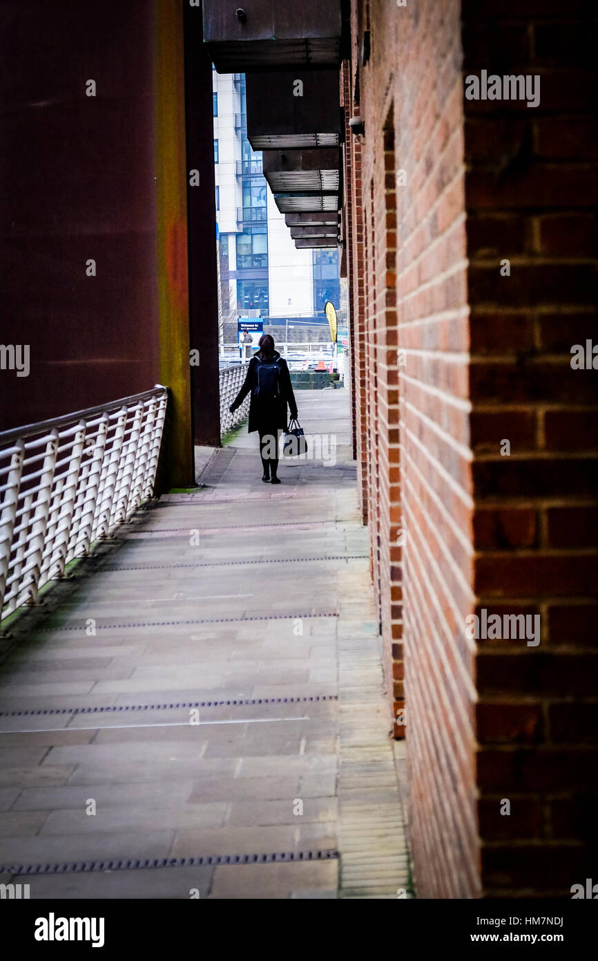 A piedi femmina per lavorare in The Granary Wharf area di Leeds, West Yorkshire. Foto Stock