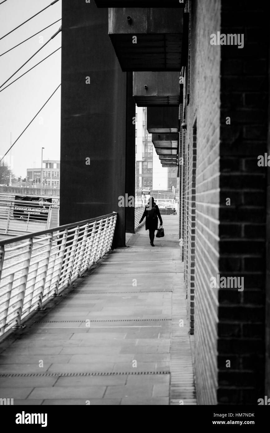 A piedi femmina per lavorare in The Granary Wharf area di Leeds, West Yorkshire. Foto Stock