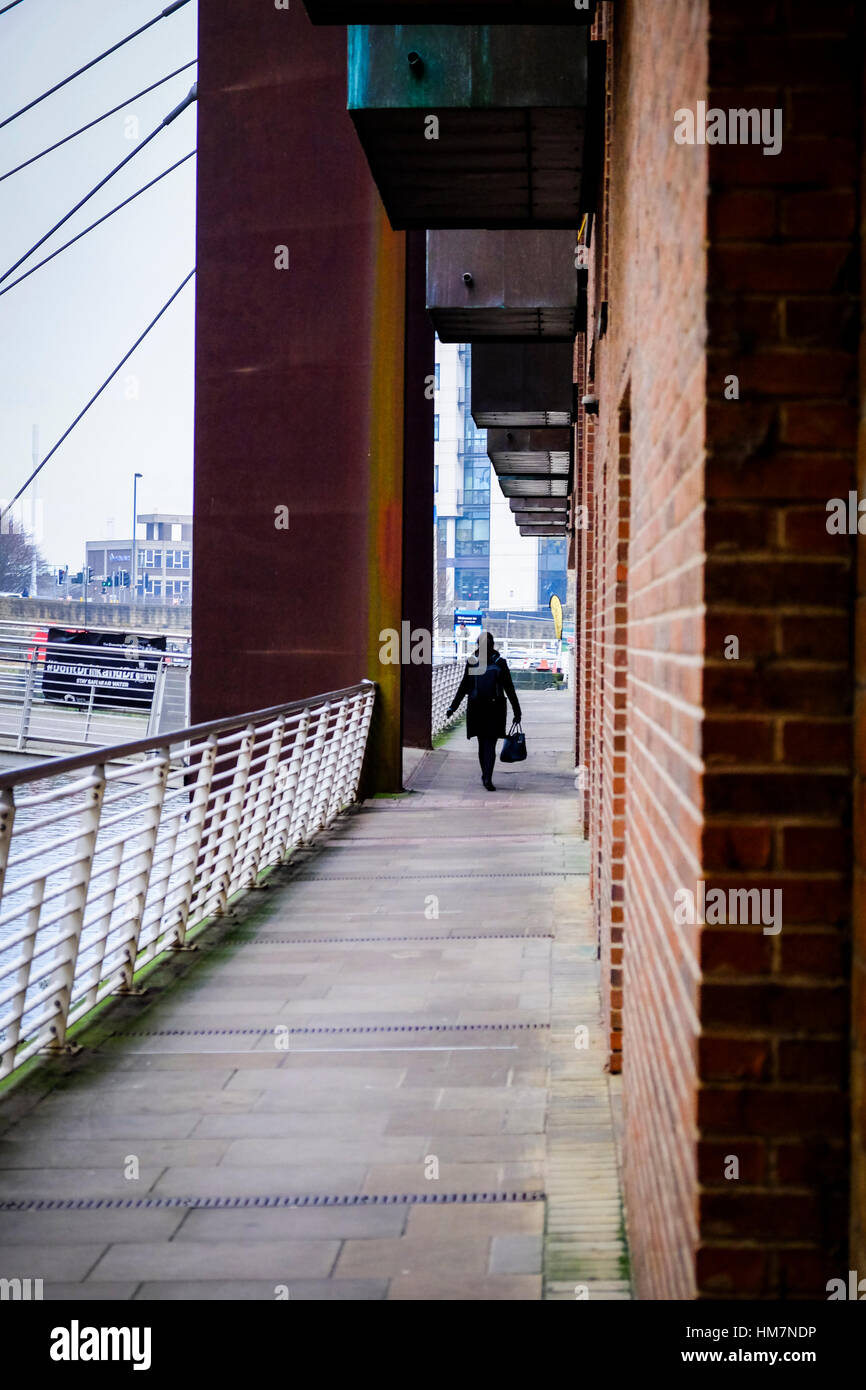 A piedi femmina per lavorare in The Granary Wharf area di Leeds, West Yorkshire. Foto Stock