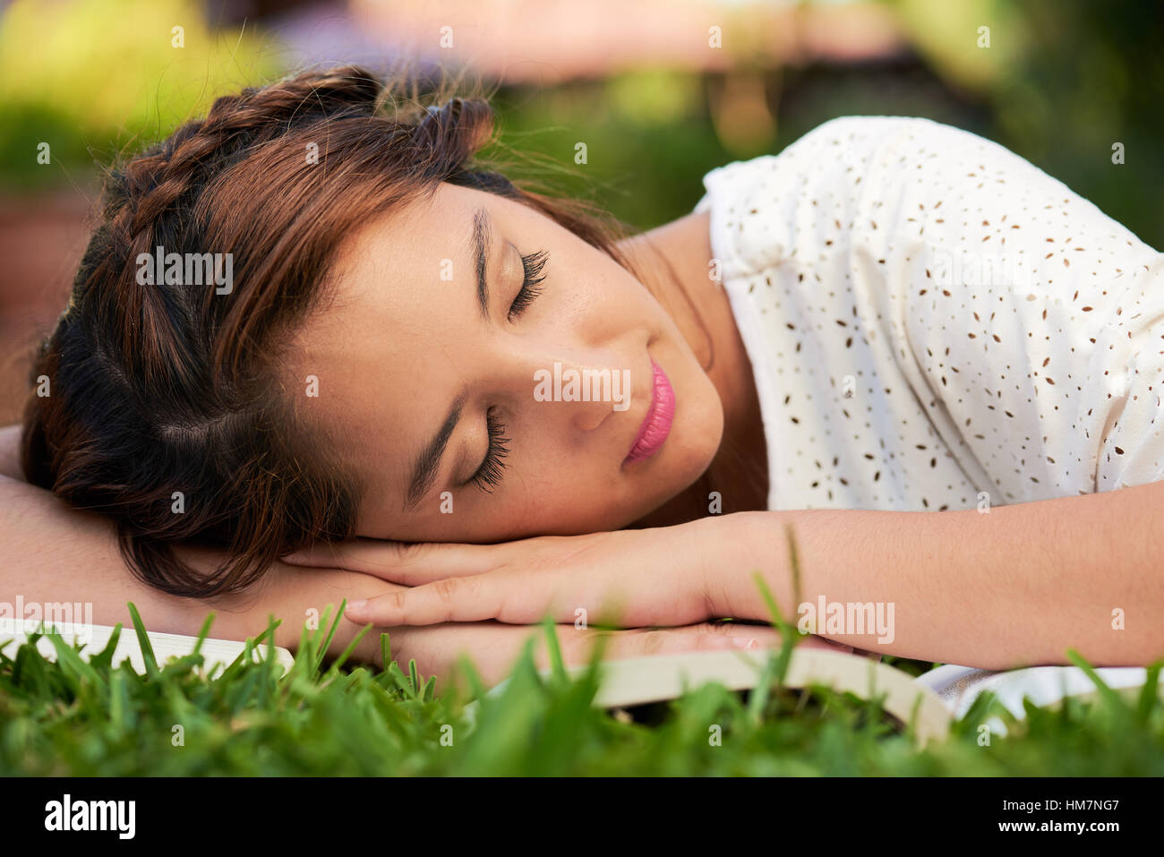 Ragazza dorme sulla sommità di libri in un parco Foto Stock