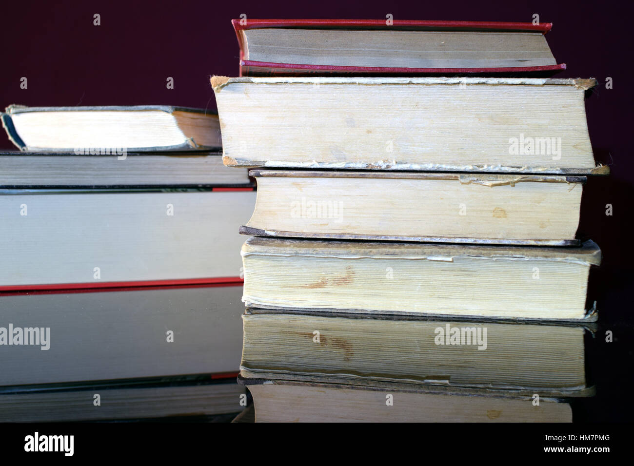 Pila di libri vecchi su nero tavolo specchiante. Foto Stock