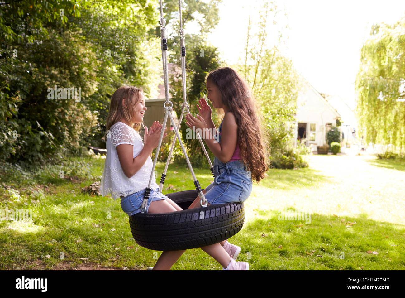 Due ragazze seduta su swing giocante battimani gioco Foto Stock