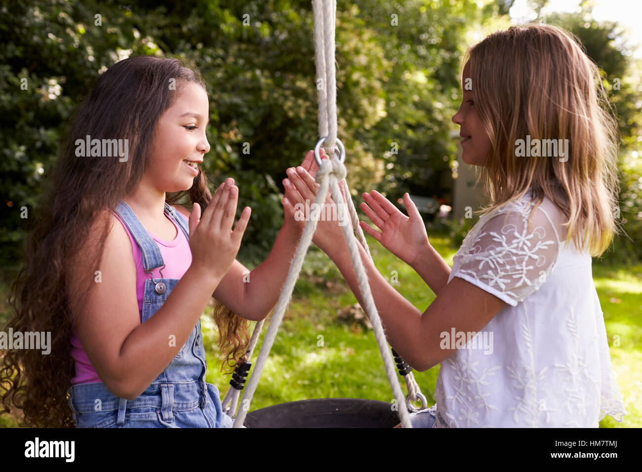 Due ragazze seduta su swing giocante battimani gioco Foto Stock