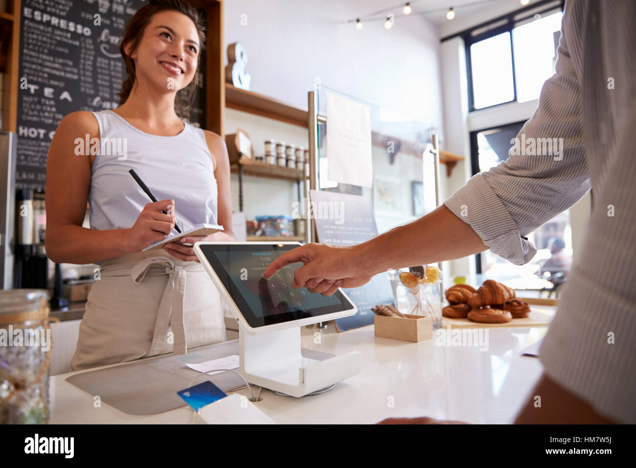 Il cliente usando il touch screen per effettuare il pagamento presso un negozio di caffè Foto Stock