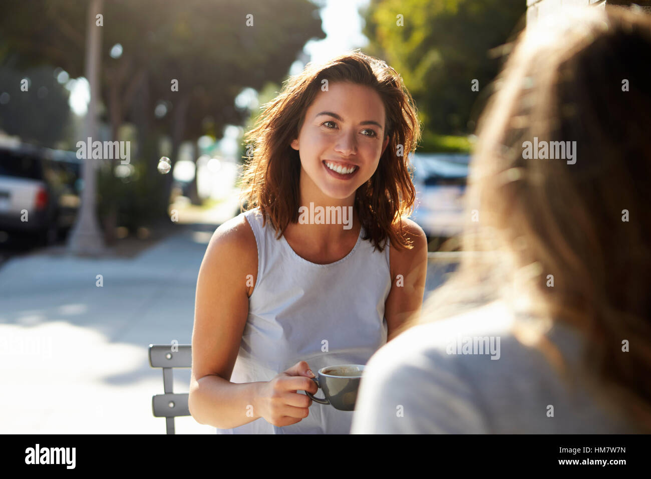 Due amiche a parlare davanti a un caffè al di fuori di un cafe Foto Stock
