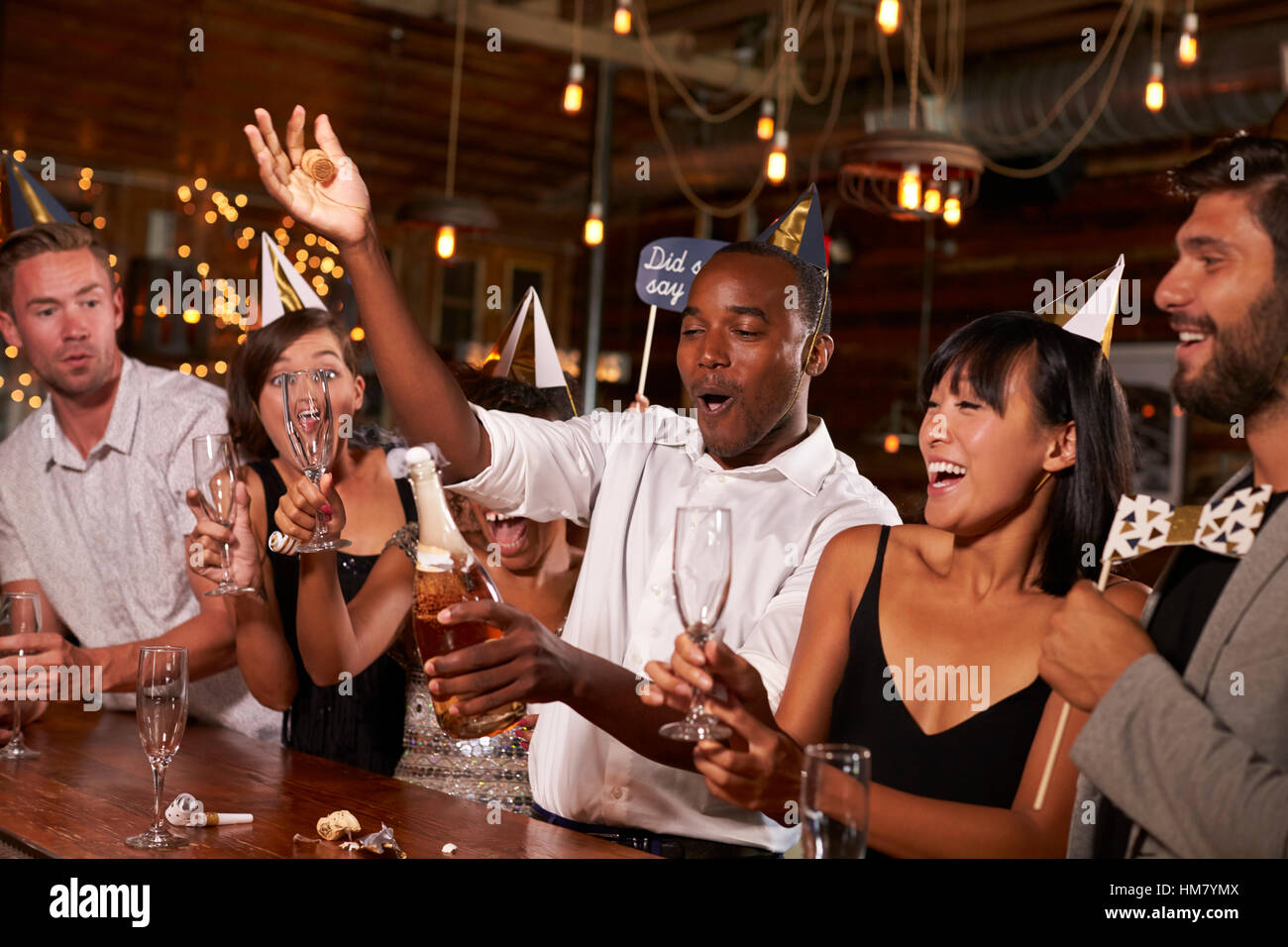 Amici stappare lo champagne a una festa di Capodanno presso un bar Foto Stock