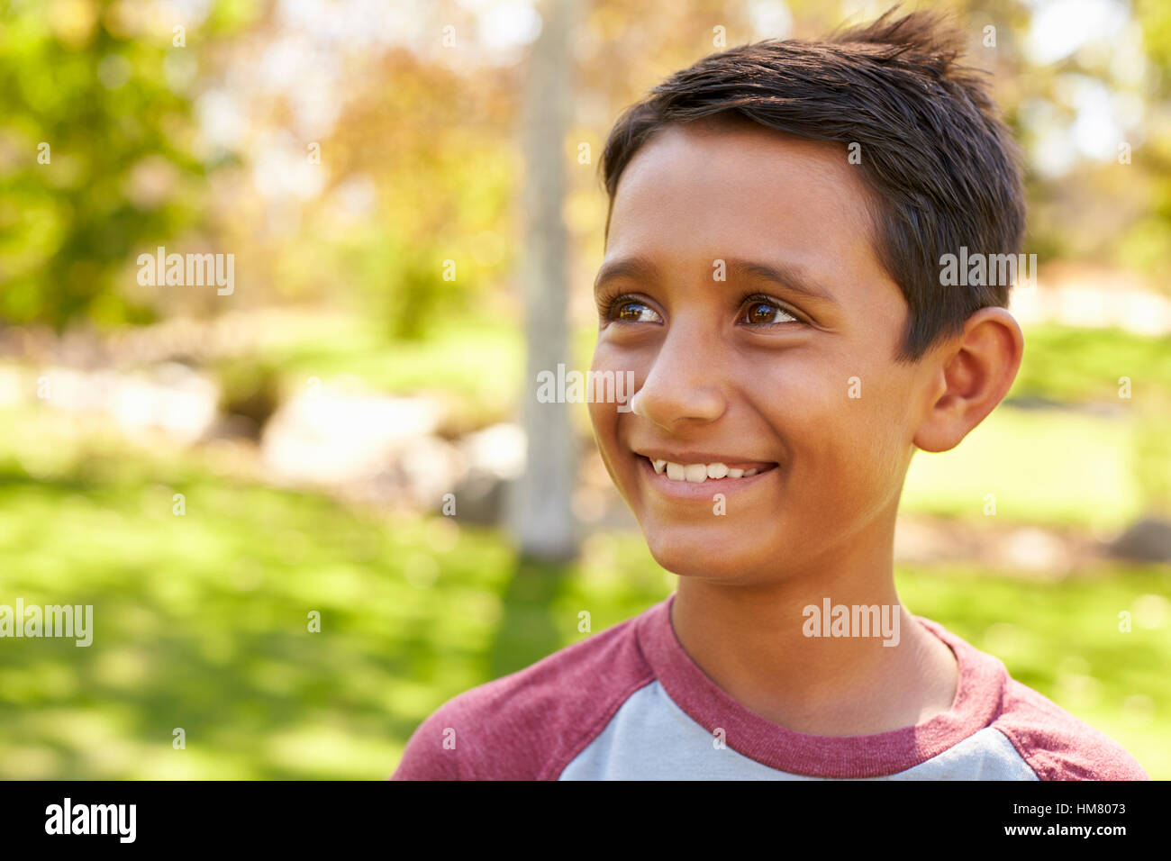 Sorridente miscelati razza caucasica ragazzo asiatico nel parco che guarda lontano Foto Stock