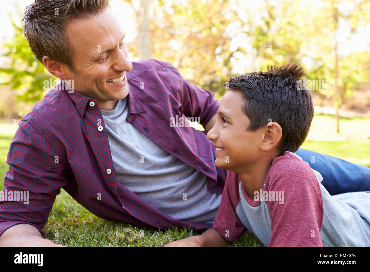 Razza mista Asian boy relax nel parco con il suo padre bianco Foto Stock