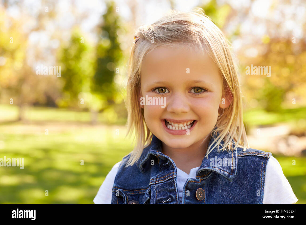 Cinque anni ragazza bionda in un parco di sorridere alla telecamera Foto Stock