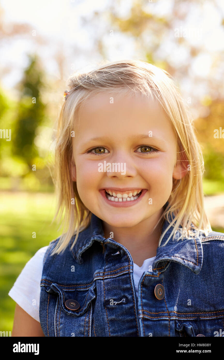 Cinque anni ragazza bionda in park sorride alla telecamera, verticale Foto Stock