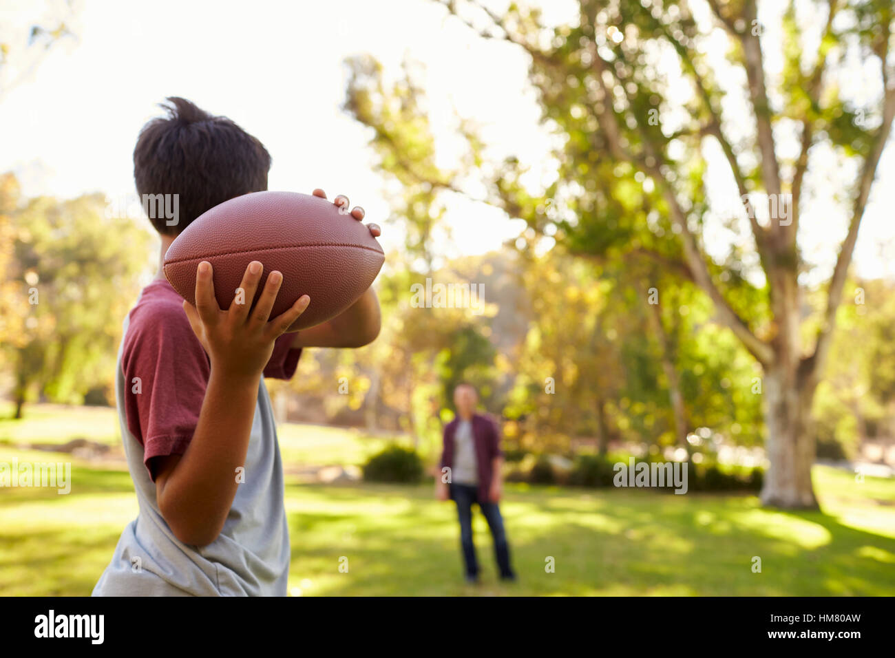 Ragazzo giovane lanciando la palla a papà nel parco, la messa a fuoco su oggetti in primo piano Foto Stock