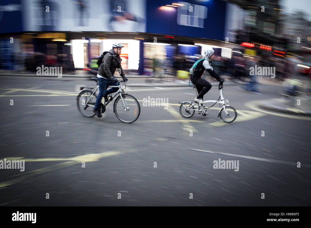 Due ciclisti pendolari fra la Piccadilly Circus a Londra centrale - sfocatura del movimento Foto Stock