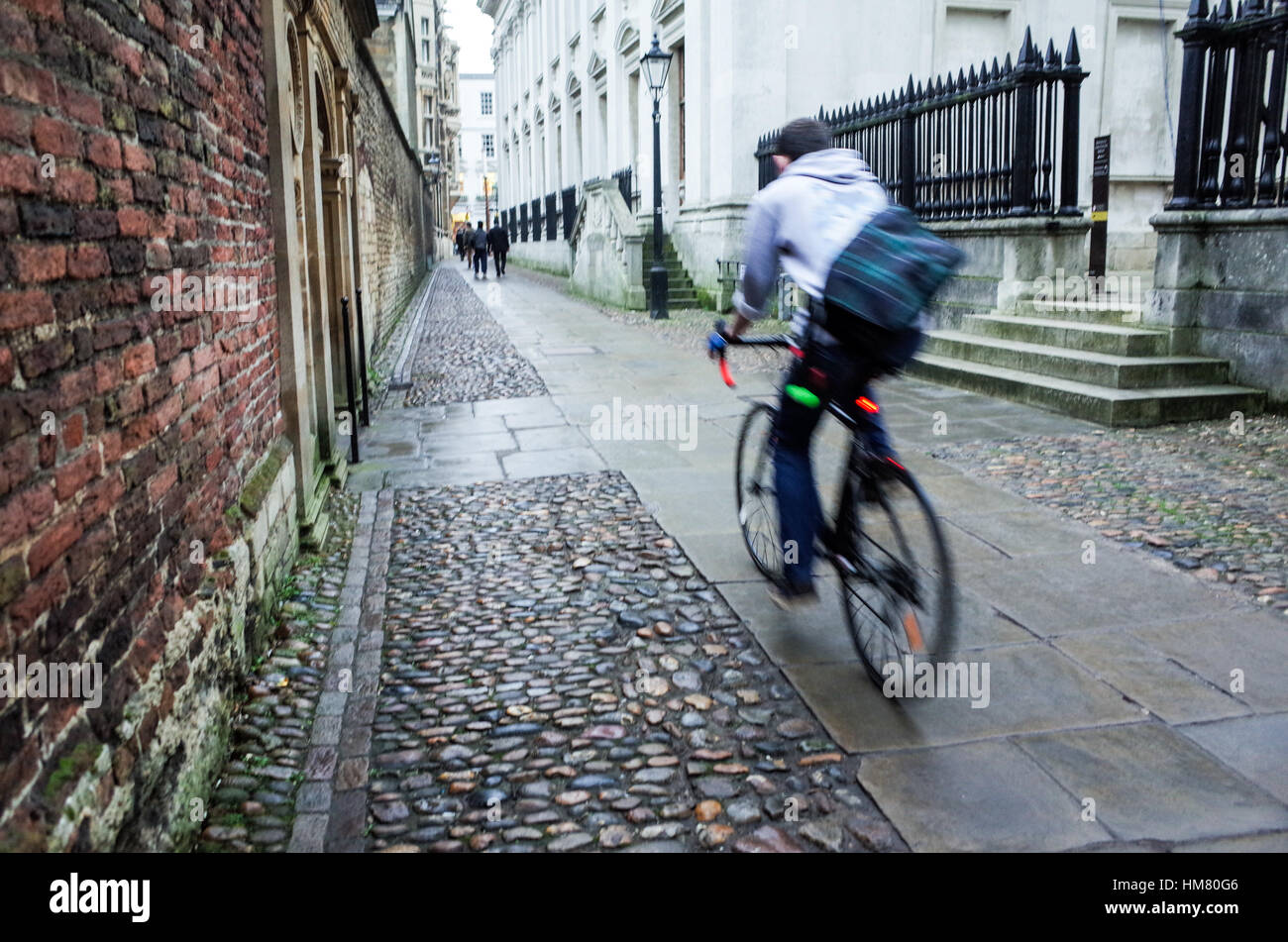 Uno studente di cicli passato edifici accademici di Cambridge City Centre Foto Stock