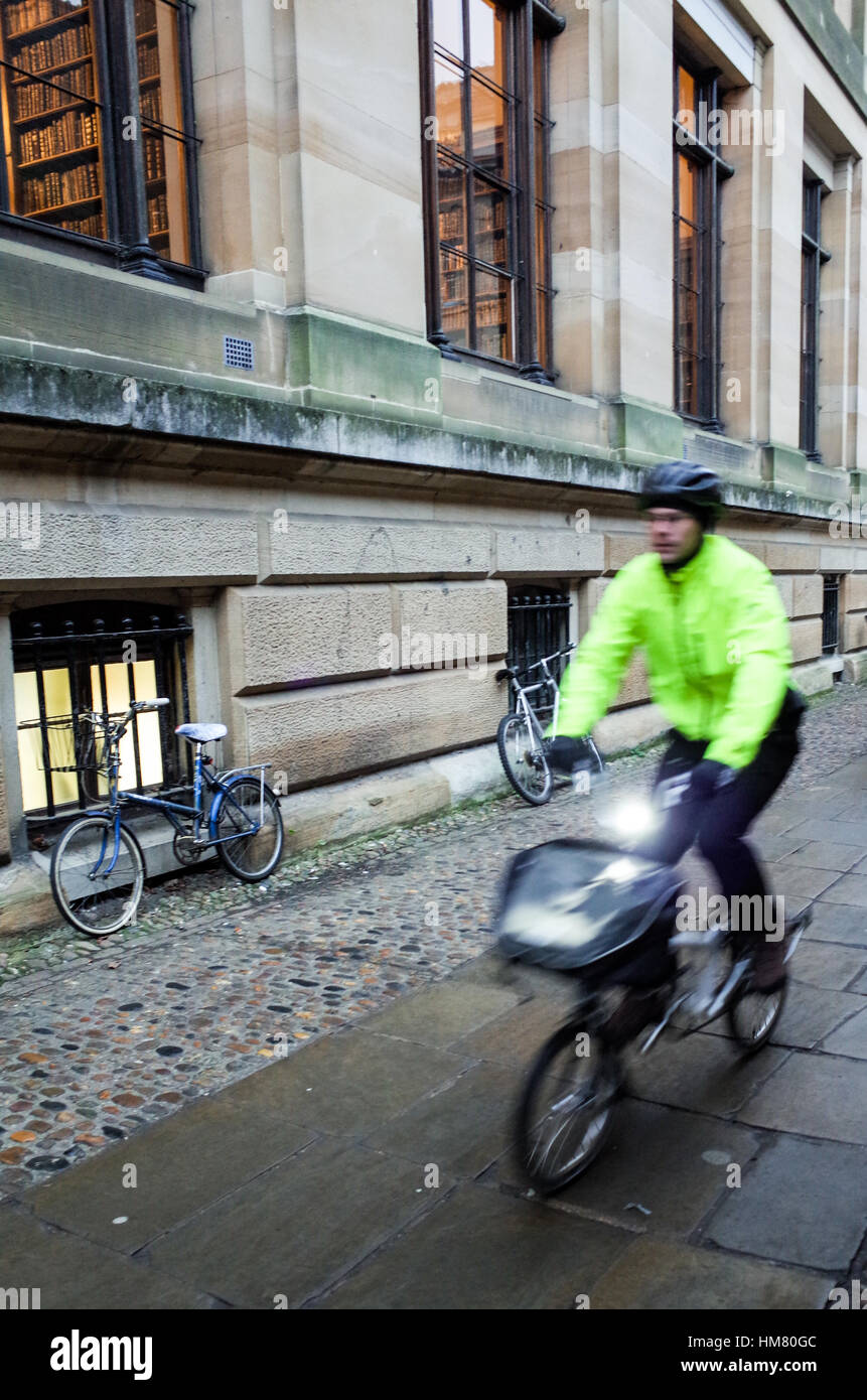 Un ciclista commuta passato edifici accademici di Cambridge Foto Stock