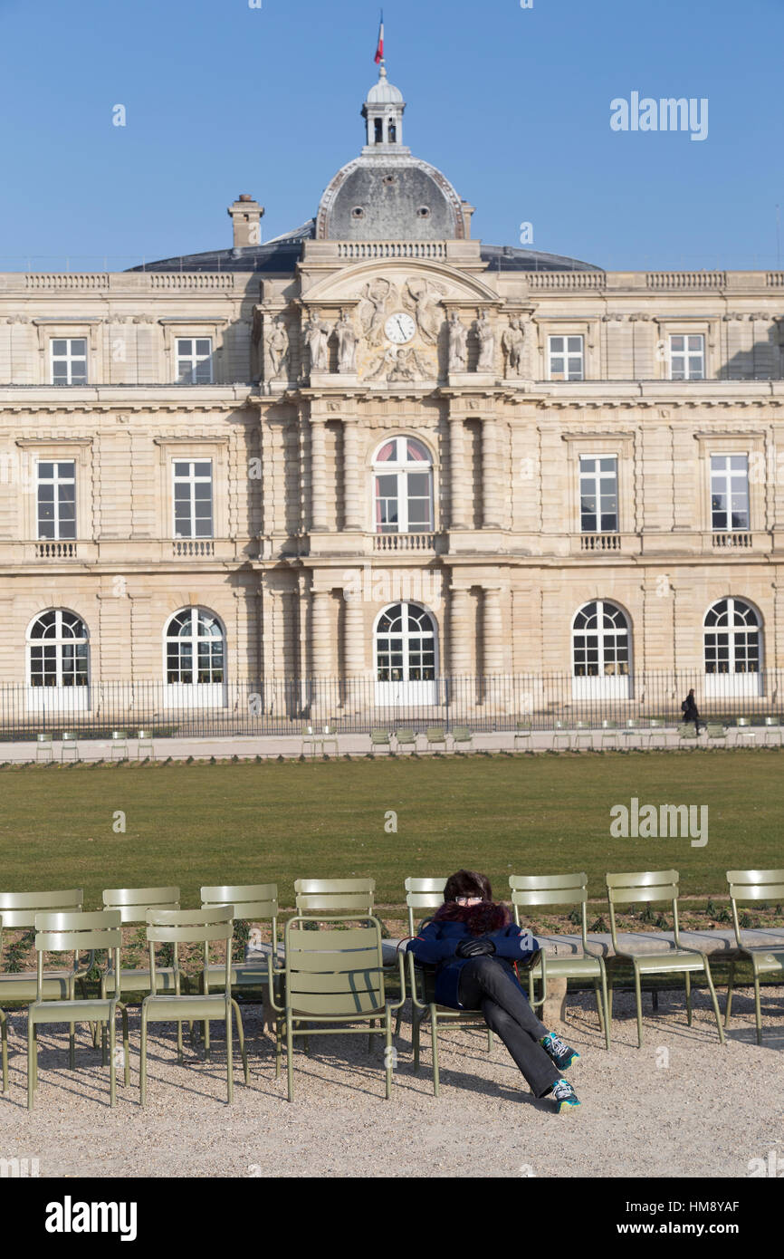 Donna godendo il sole invernale di fronte il Palazzo del Lussemburgo a Montparnasse nel XIV arrondissement di Parigi Francia Foto Stock